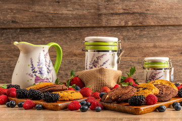 Blackberries, blueberries, raspberries, cookies and white ceramic vessels