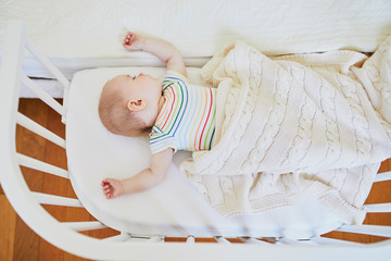 Baby sleeping in co-sleeper crib attached to parents' bed