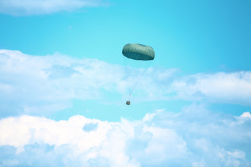 A military crate is being parachuted from a military cargo plane during a drill.