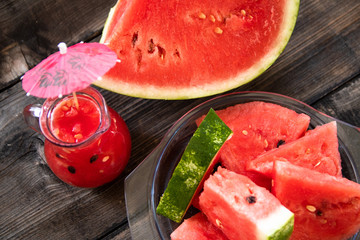 Sliced watermelon on old wooden table and watermelon smoothie in a glass bowl