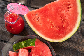 Sliced watermelon on old wooden table and watermelon smoothie in a glass bowl