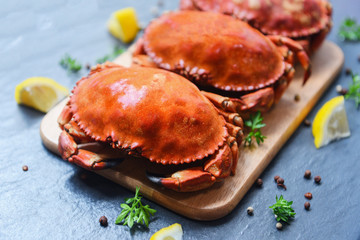 Cooked crabs on wooden board with lemon on plate served on dark plate top view - stone crab steamed seafood © Bigc Studio
