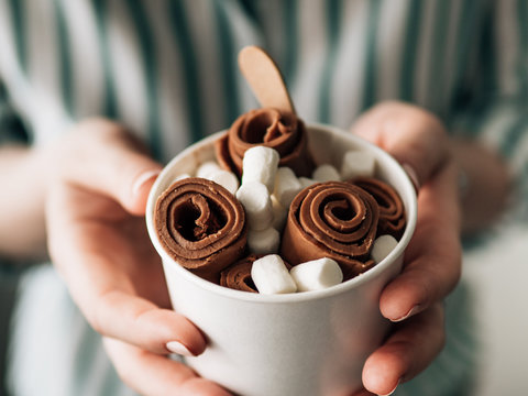 Rolled Cocolate ice cream in cone cup in woman hands. Hand holding cone cup with thai style chocolate rolled ice cream