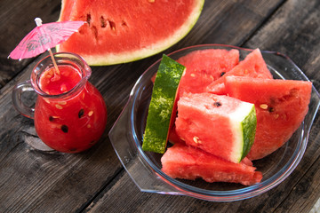 Sliced watermelon on old wooden table and watermelon smoothie in a glass bowl