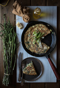 From above of skillet pan with fried tortilla with fresh asparagus and onion served on board with ingredients