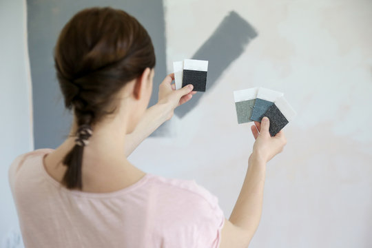 Young woman choosing a perfect shade of grey for walls in her new home