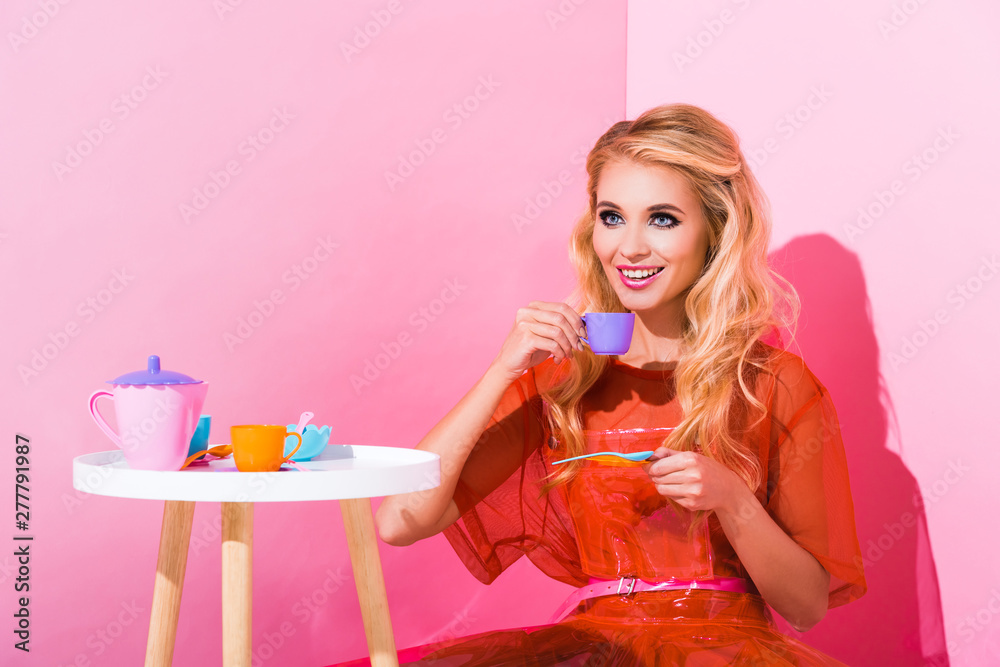 Wall mural beautiful smiling girl with toy cup on pink, doll concept