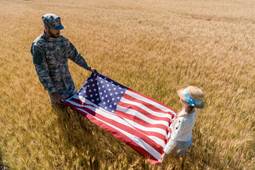 overhead view of soldier in uniform and kid holding american flag in field