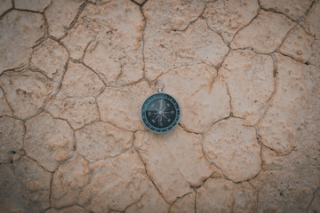 Big compass on dry cracked desert area
