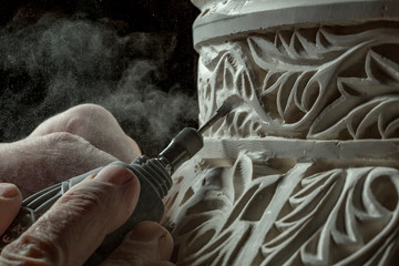 Dirty hands carving ornament on stucco surface