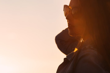 silhouette of a girl with glasses. evening sky and sunshine
