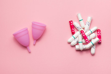 Two reusable silicone menstrual cups and heap of tampons comparison on a soft pink background. Modern female intimate alternative gynecological hygiene. Eco zero waste concept