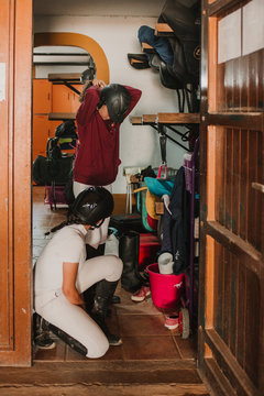 Side view of women in closet with staff getting dressed for horse riding