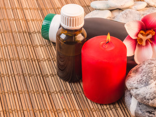 Spa background with red candle, massage oils and stones