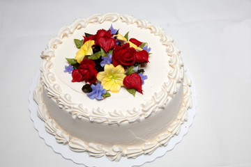 Lovely white frosted layer cake with yellow, red and blue flowers on top probably made from frosting. St Paul Minnesota MN USA
