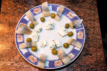 Polish hors d'oeuvre snack plate with circle of herring fish, blue cheese, and green olives. Zawady Poland