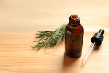 Bottle of natural tea tree oil, dropper and plant on table, space for text