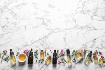 Flat lay composition with bottles of natural tea tree oil and space for text on white marble...