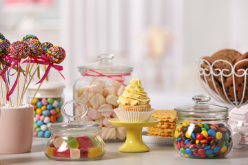 Candy bar with different sweets on white table against blurred background