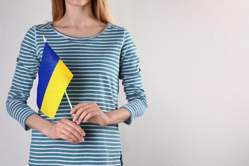 Woman holding Ukrainian flag against light background, closeup with space for text. International relationships