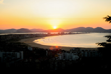 Sunset in a wonderful image of a coastal town, river flowing into a beach bathed by the sunset sun. Laredo, Cantabria, Spain