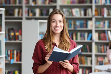 Young pretty woman with book in library