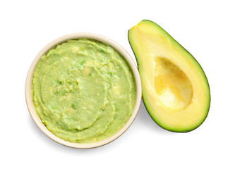 Bowl of tasty guacamole and cut avocado on white background, top view