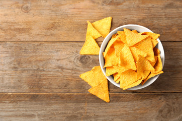 Tasty mexican nachos chips in bowl on wooden table, flat lay. Space for text