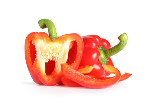 Cut and whole ripe red bell peppers on white background