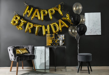 Room interior with gift boxes and phrase HAPPY BIRTHDAY made of golden balloon letters
