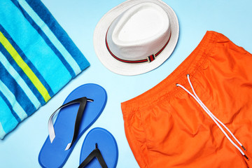 Flat lay composition with stylish male swim trunks on color background. Beach objects