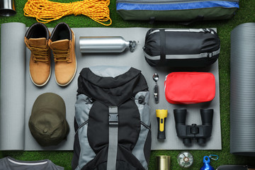 Flat lay composition with different camping equipment on green grass