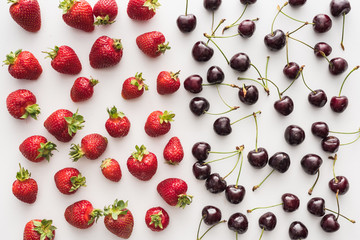 Naklejka na ściany i meble top view of sweet and fresh cherries and whole strawberries on white background