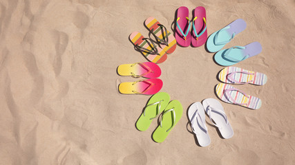 Flat lay composition with flip flops on sand, space for text. Summer beach accessories