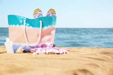 Stylish beach accessories on sand near sea. Space for text