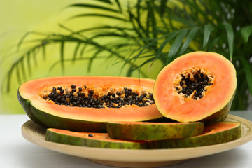 Plate with fresh juicy cut papayas on white table against blurred background, space for text