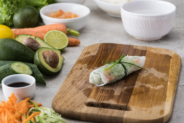 spring roll on cutting board with onion among ingredients