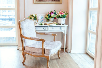 Beautiful luxury classic white bright clean interior bedroom in baroque style with large window, armchair and flower composition