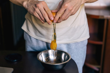  broken egg in hands, yolk falling down. Closeup. man is prepari