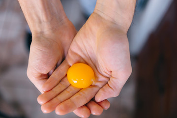 Top view on the hands of a woman with raw yolk