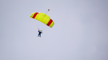 Fototapeta na wymiar jump with a tandem colored parachute on a blue sky with white clouds, adrenaline and risk.
