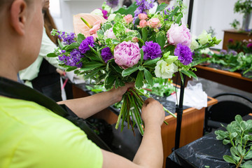 Female florist create a bouquet at workplace. Floristics workshop. Making beautiful flower bouquets...