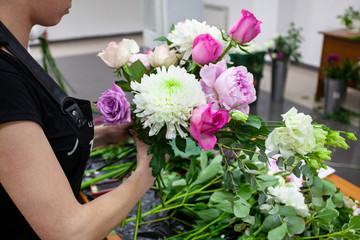Female florist create a bouquet at workplace. Floristics workshop. Making beautiful flower bouquets...