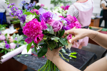 Female florist create a bouquet at workplace. Floristics workshop. Making beautiful flower bouquets and floral decorations..