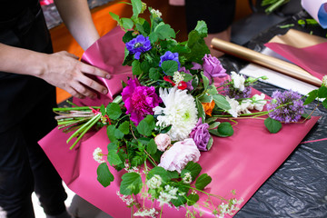 Female florist create a bouquet at workplace. Floristics workshop. Making beautiful flower bouquets...