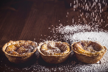 Delicious Belem cakes with icing sugar on a rustic table
