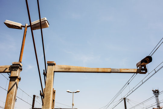 Surveillance camera, wires, towers, and streetlights on the railway.