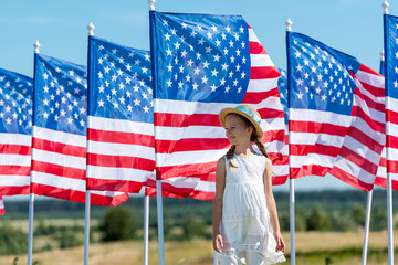 cute patriotic kid standing in white dress near american flags