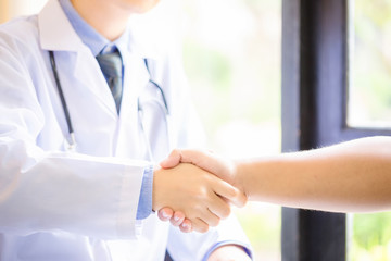 Doctor and patient in the office shaking hands, healthcare and assistance concept