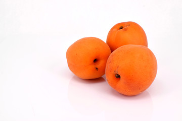 Nahaufnahme von drei reifen Aprikosen. Freigestellt vor weißem Hintergrund.